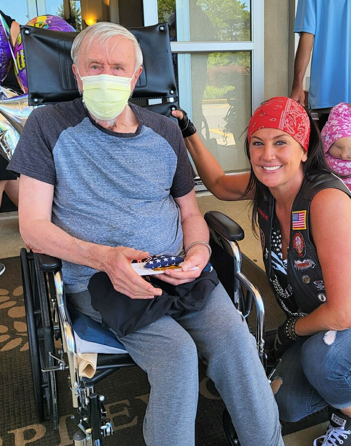 man in wheelerchair with biker girl kneeling next to him