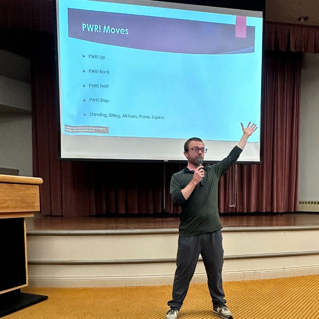 man with arm raised in front of big screen