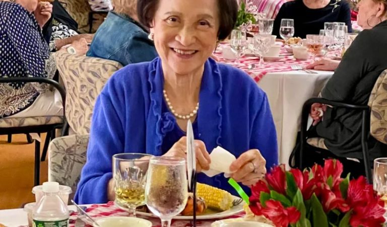 smiling woman in blue jacket eating dinner