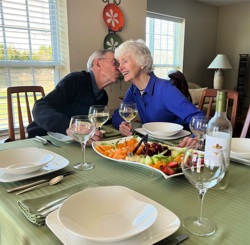 man kissing woman on cheek while toasting