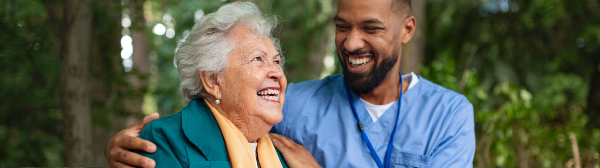 A senior woman and a male nurse laughing together.