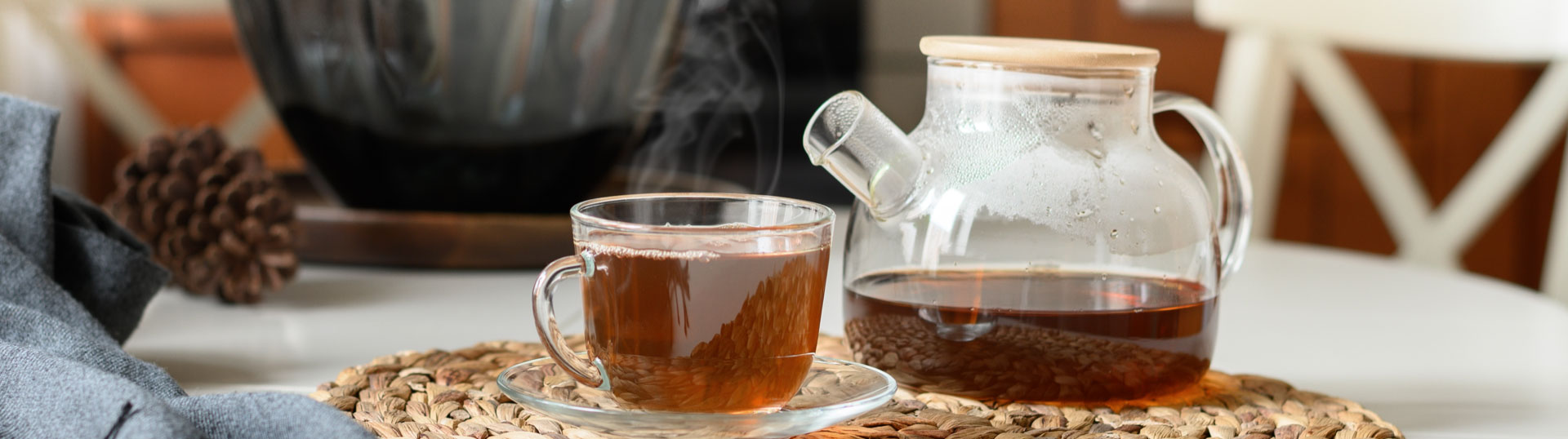 Close up of a glass tea pot and cup of tea.