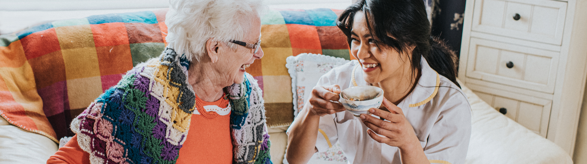 2 women smiling & drinking coffee