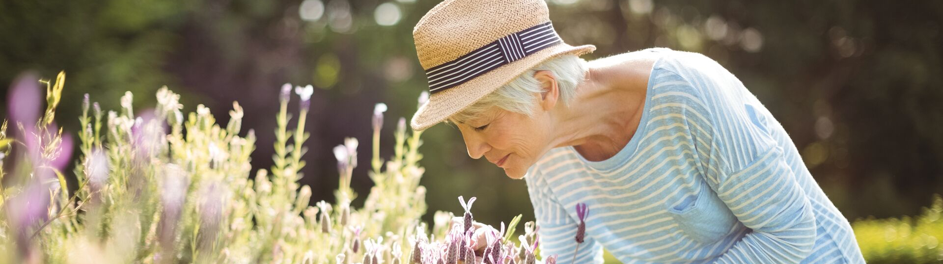 woman in hat smelling flowers