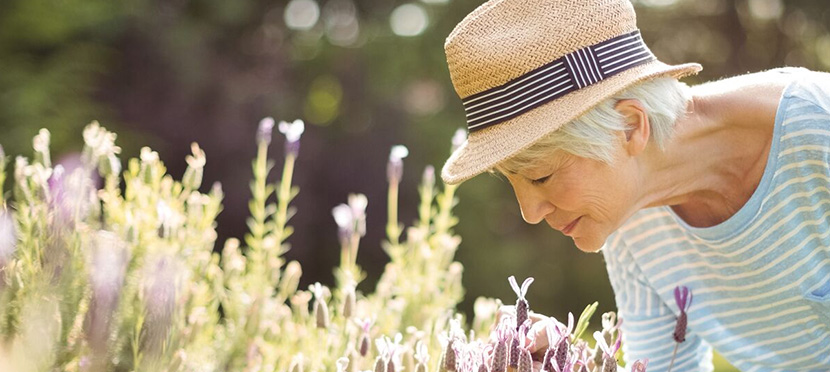 woman in hat smelling flowers