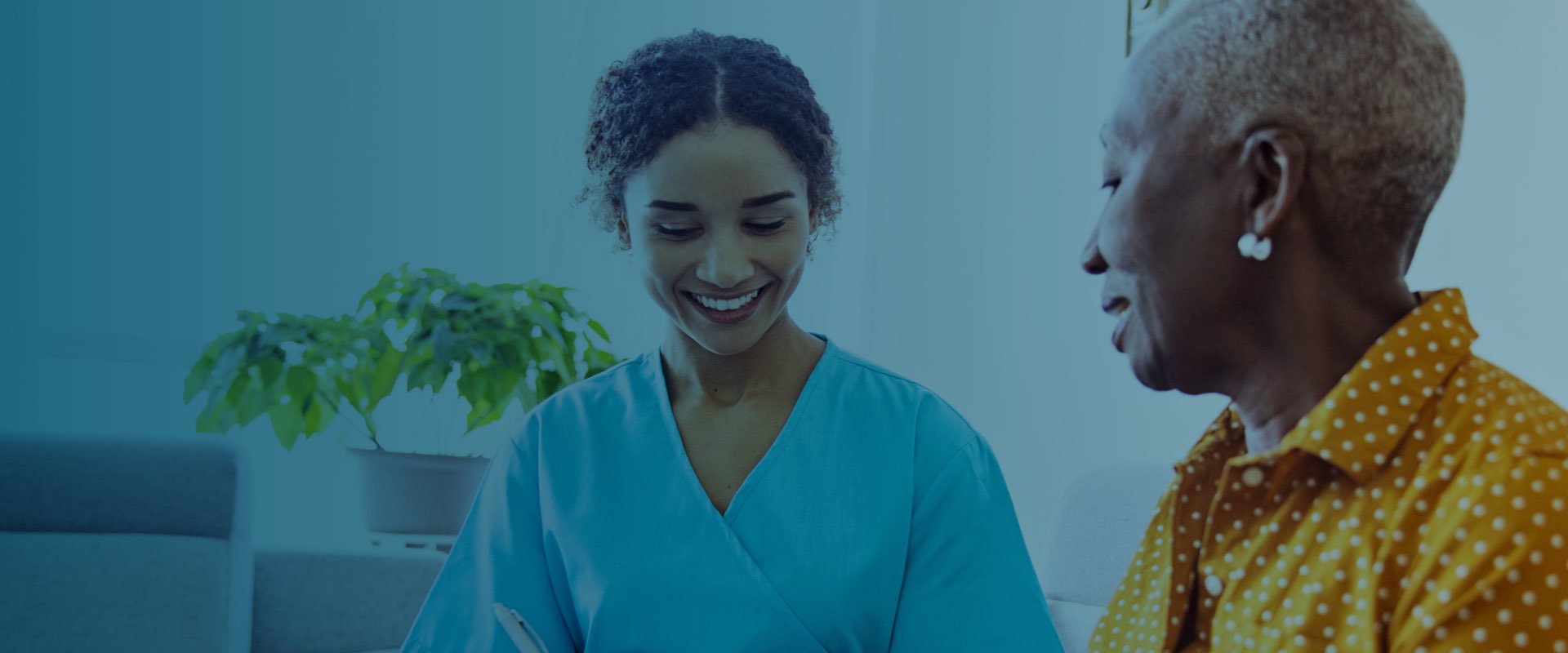 happy female nurse and an elderly female patient having a conversation