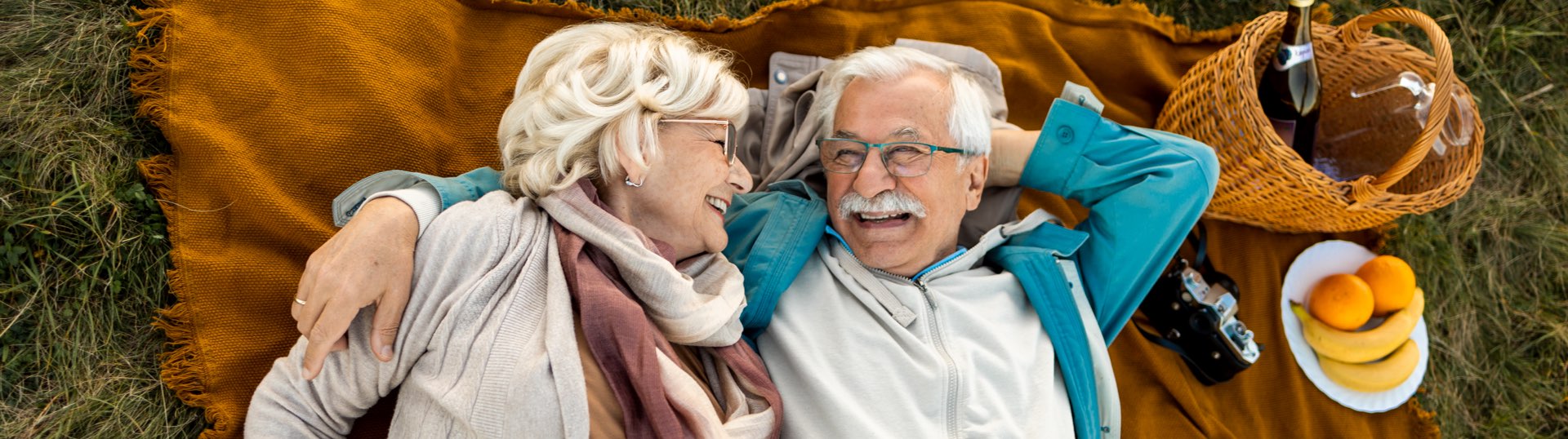 couple laying down & smiling/hugging on blanket