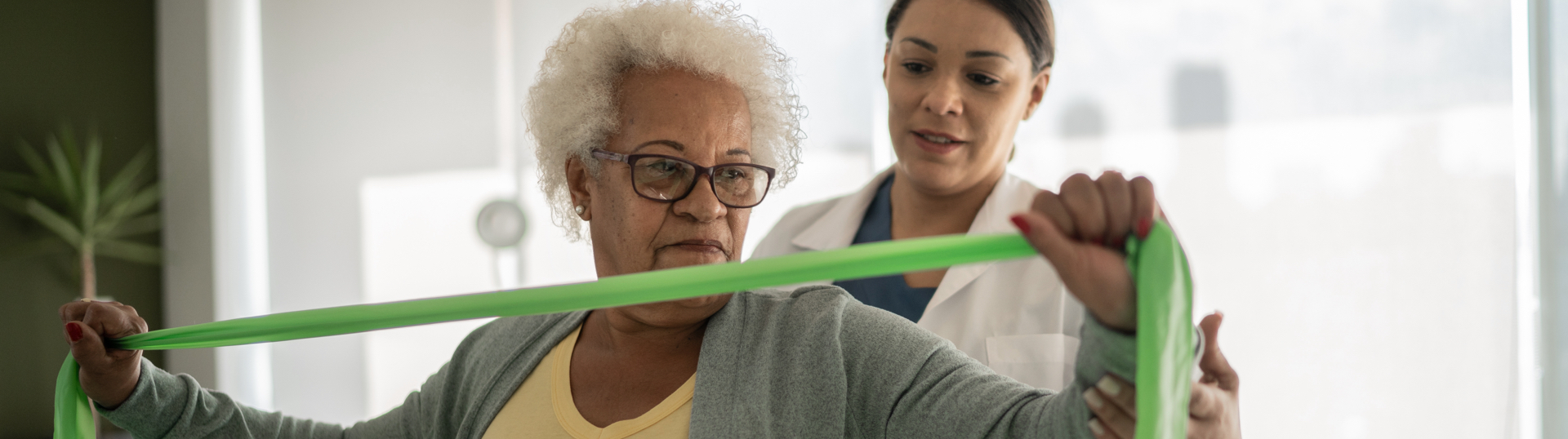 pt helping elderly woman stretch with band