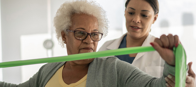 pt helping elderly woman stretch with band