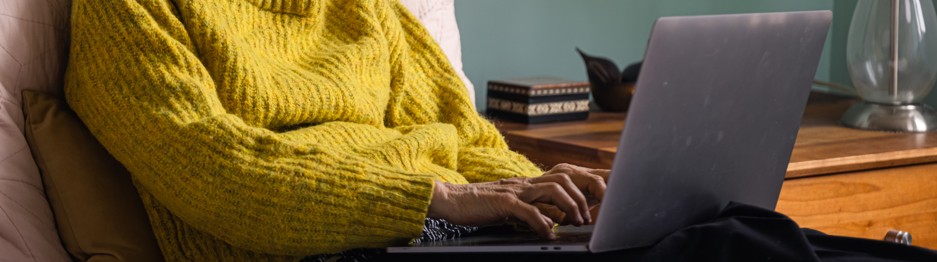 woman in yellow sweater on laptop