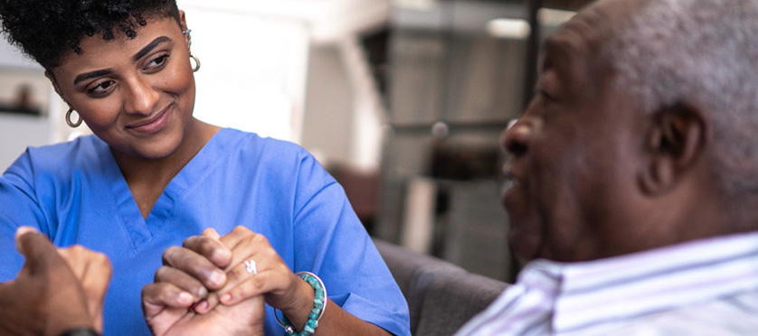 nurse holding elderly mans hands