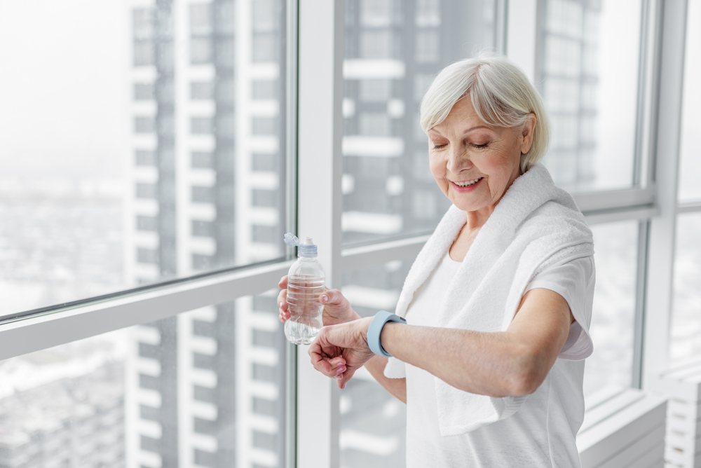 A senior woman checks her fitness tracker after exercising.