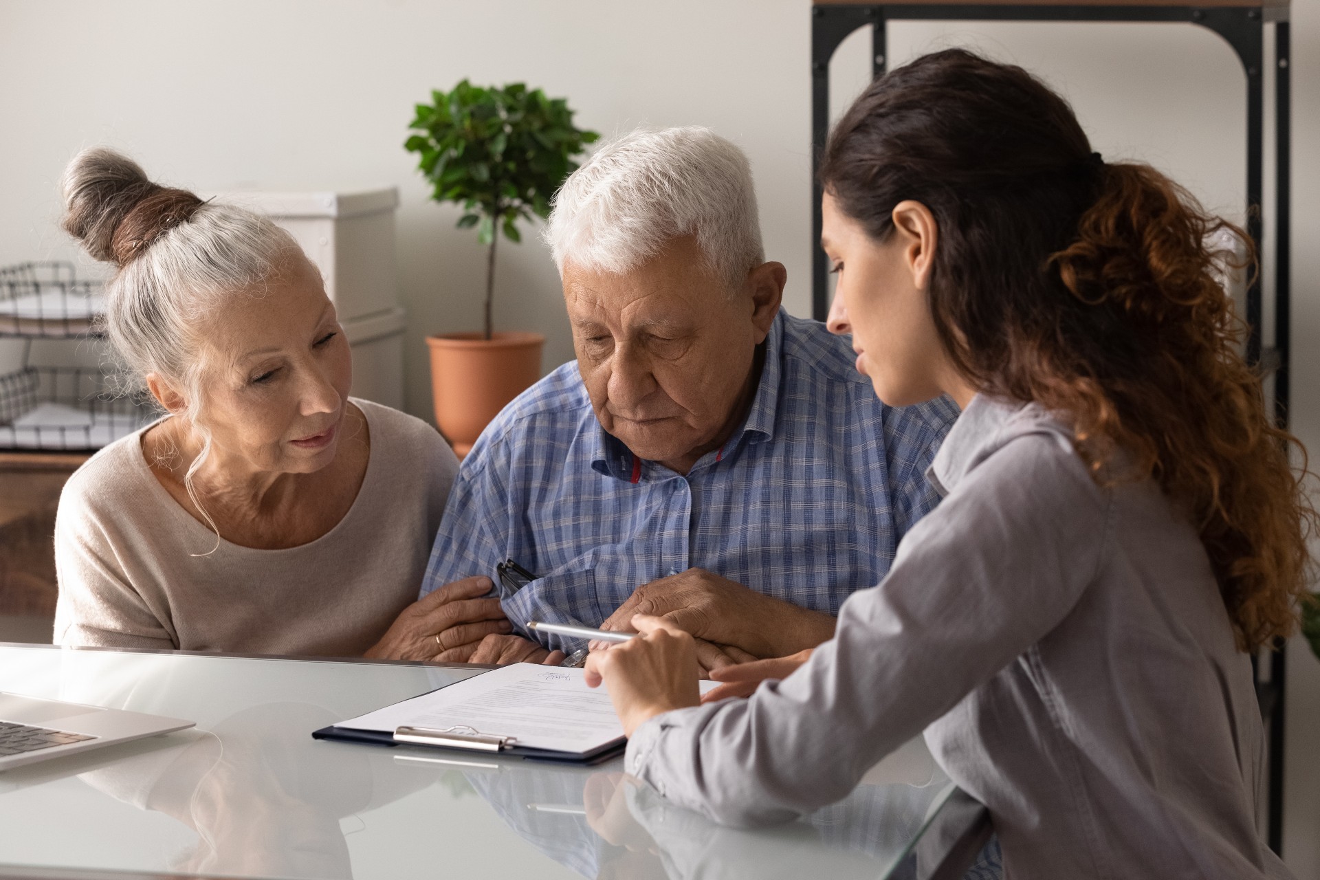 A senior couple look at paperwork with a female care coordinator.