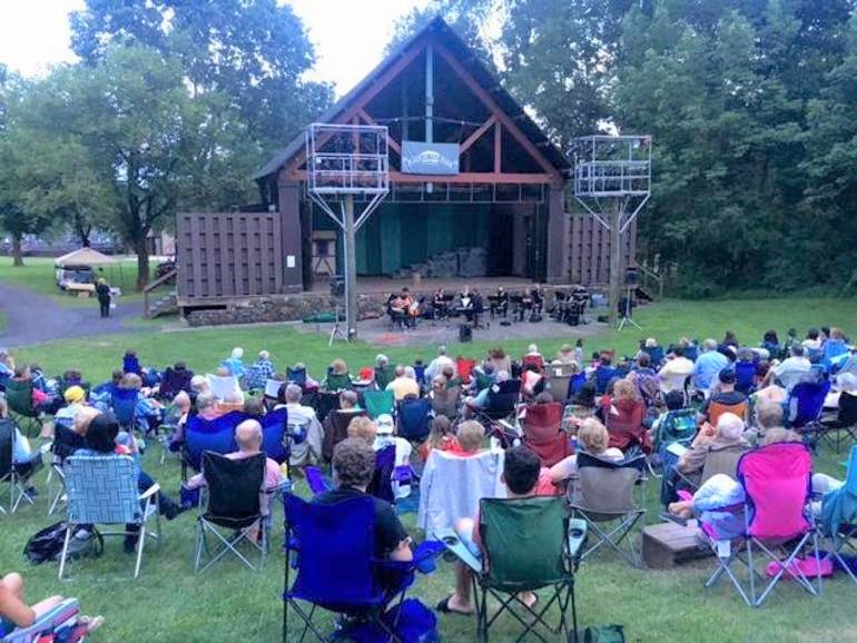 A group of people sitting in lawn chairs enjoying an outdoor concert.