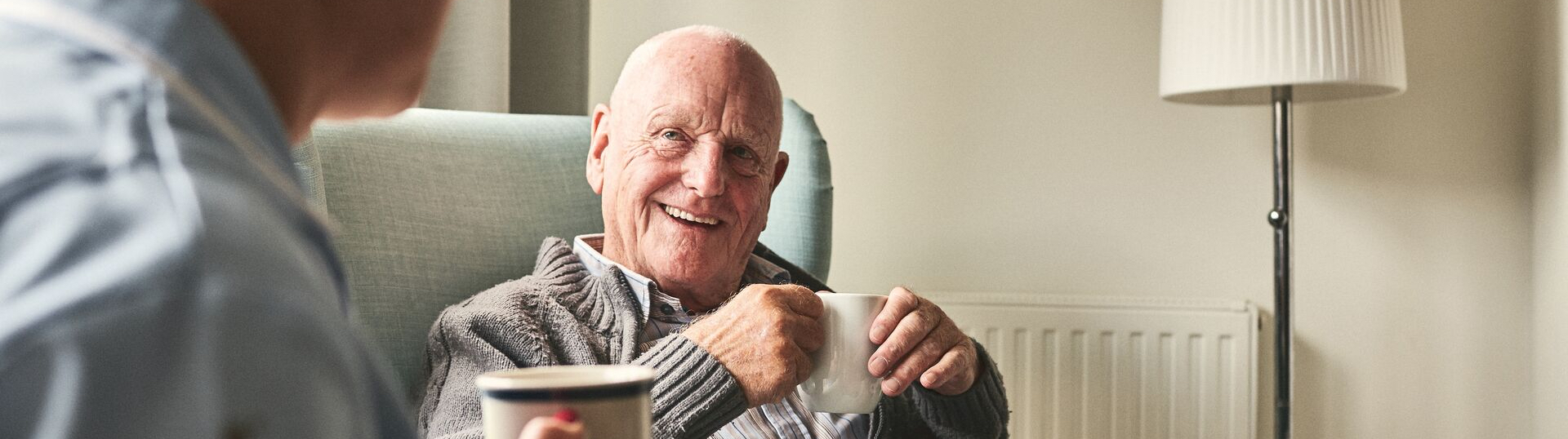 elderly man enjoying a cup of coffee with a nurse