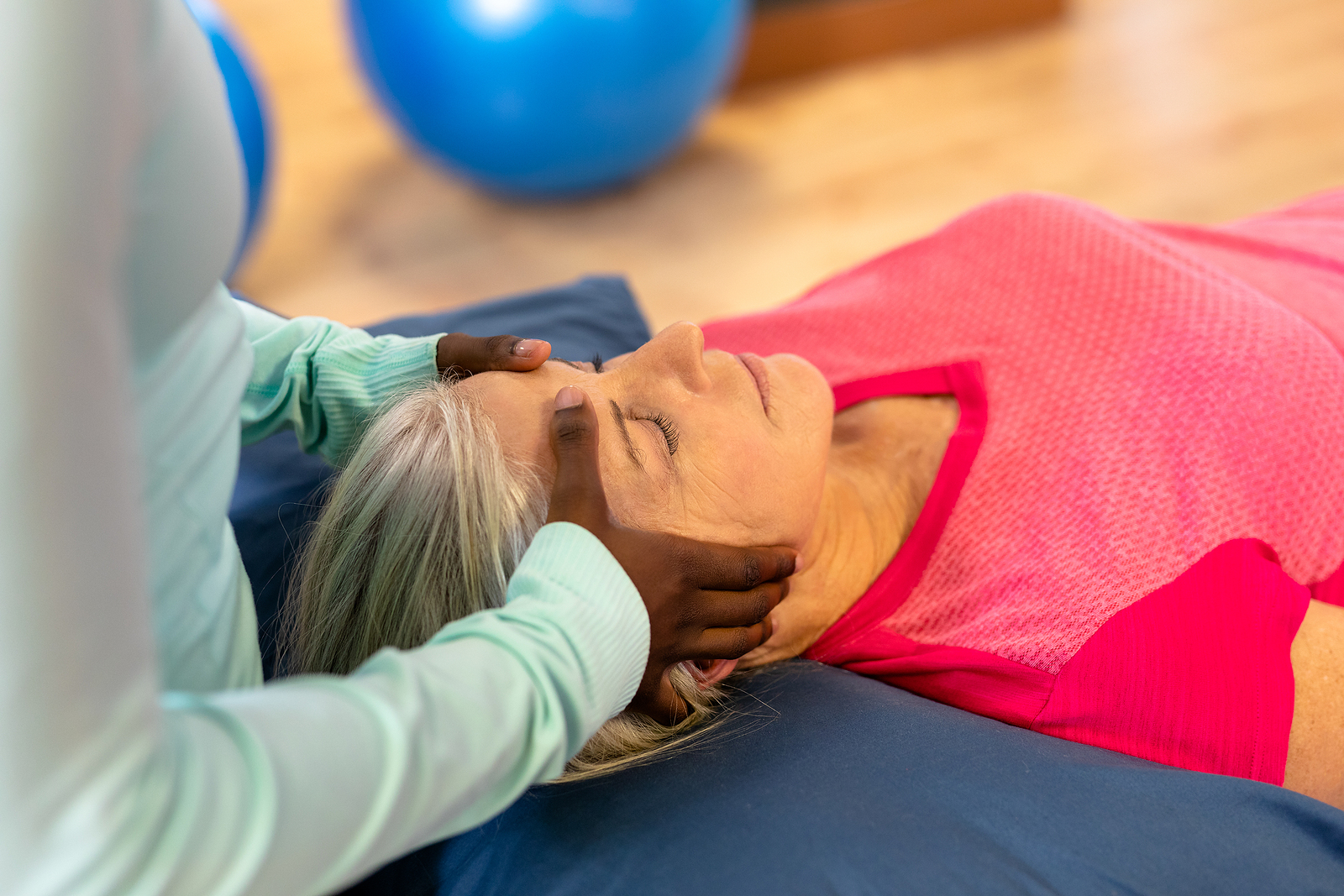 A senior woman laying with her eyes closed while receiving a massage therapy session.