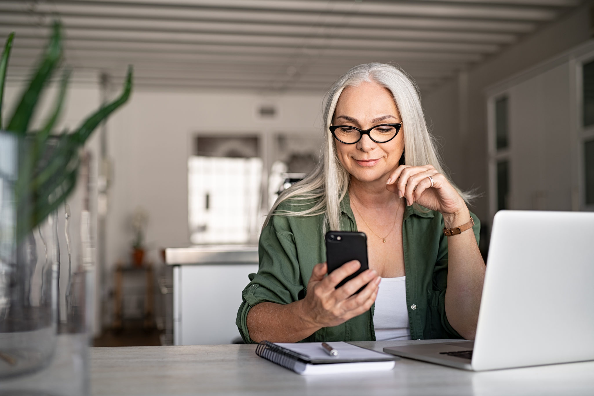 senior looking at a smart phone and laptop