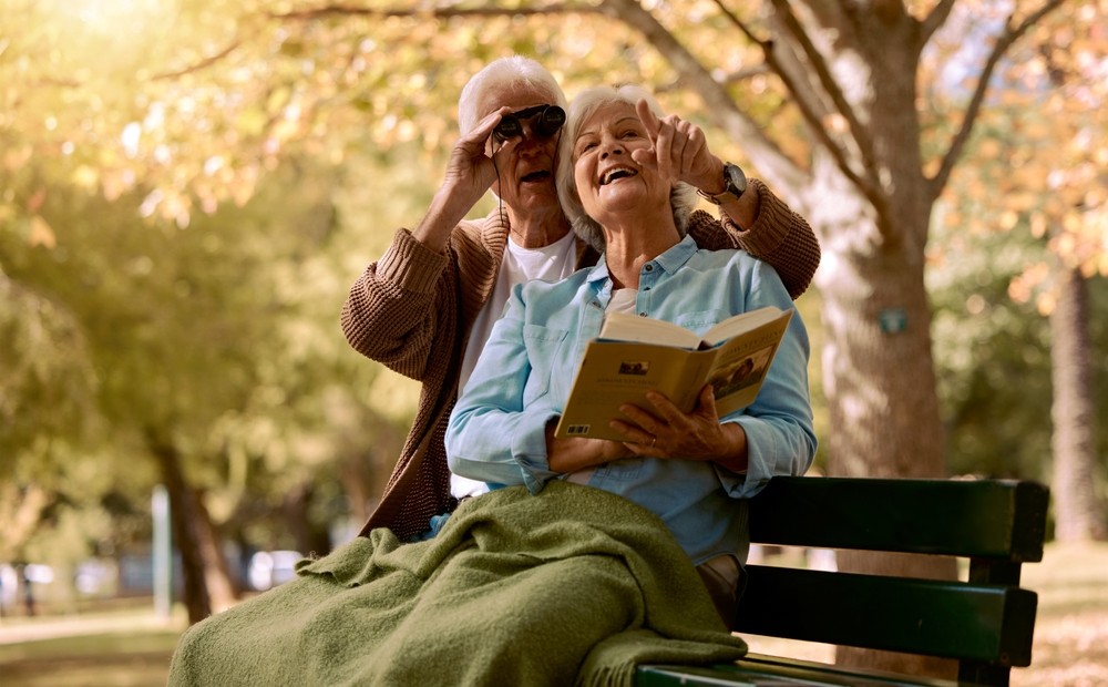 Senior couple birdwatching and reading book