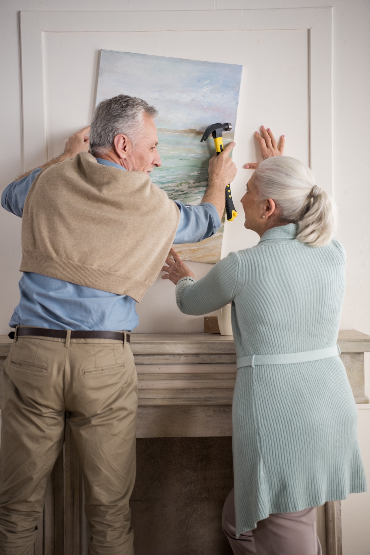 senior couple hanging up a photo on the wall