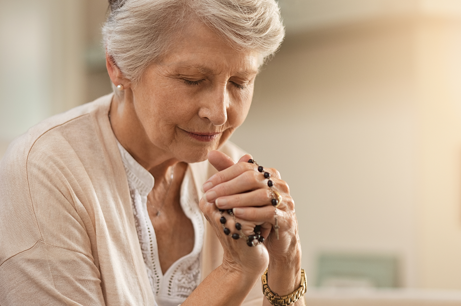 A senior woman prays with her rosary.