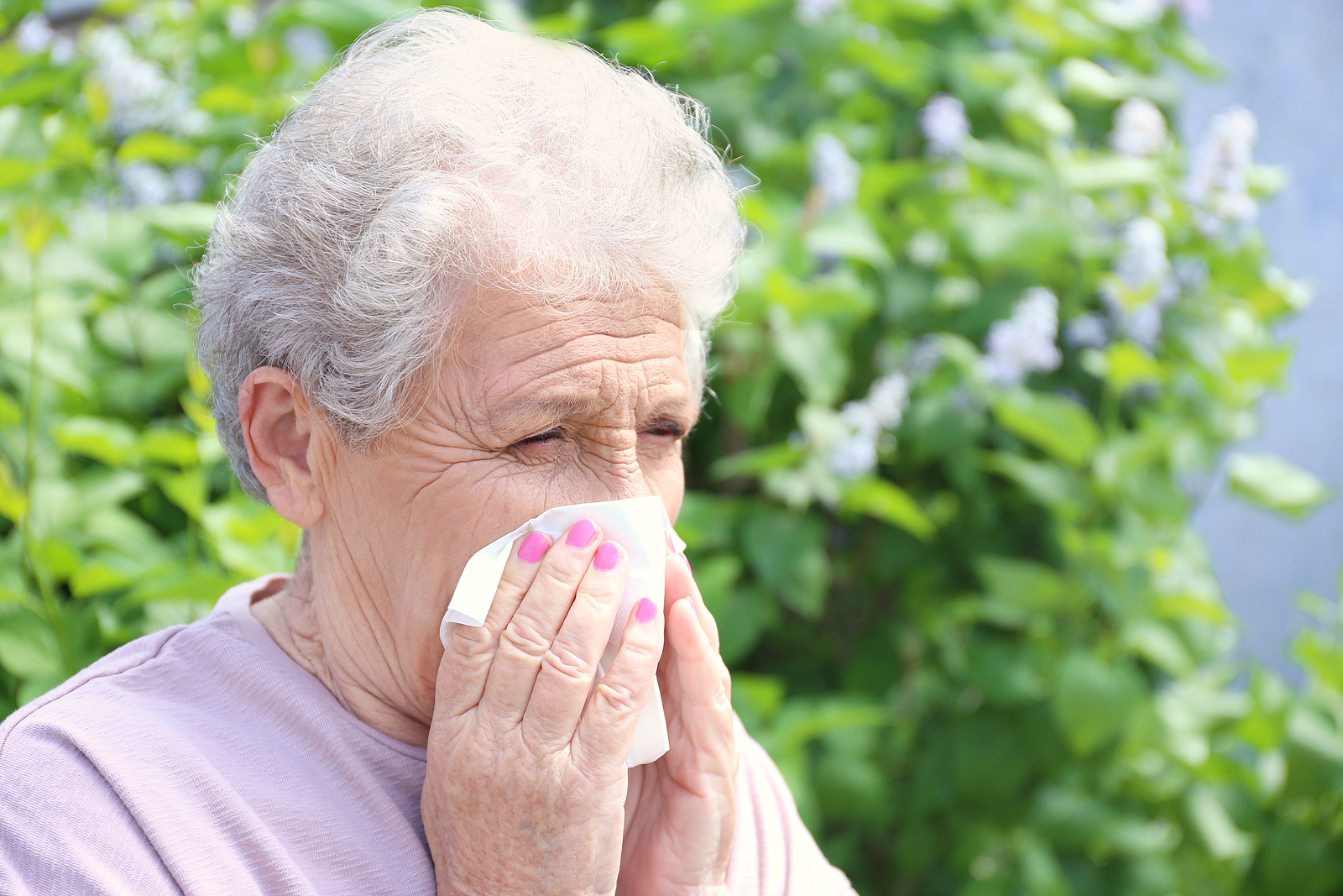 A senior woman blowing her nose.