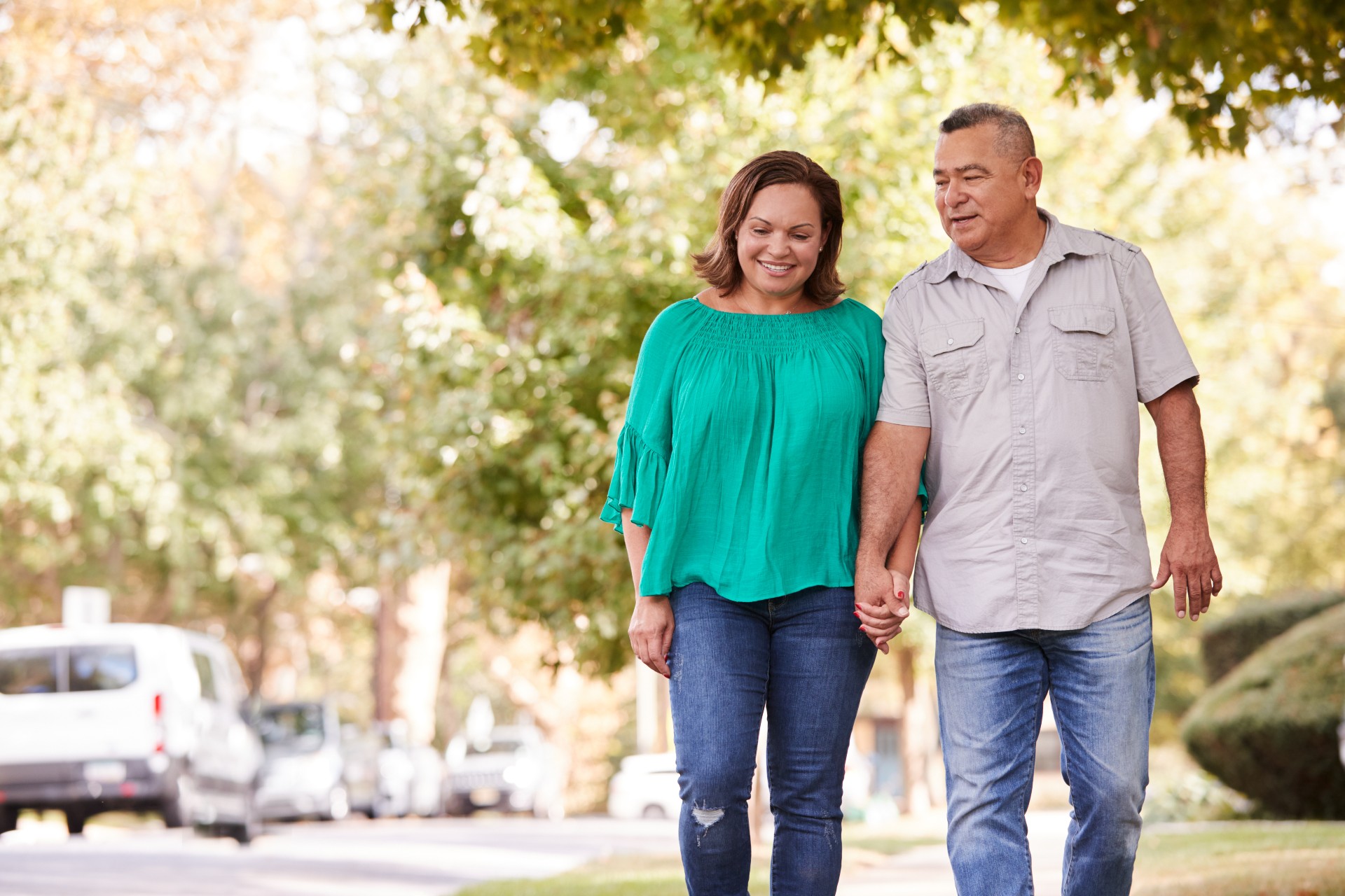 A senior couple walk hand-in-hand around the neighborhood.