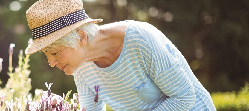 senior bending down to smell the flowers