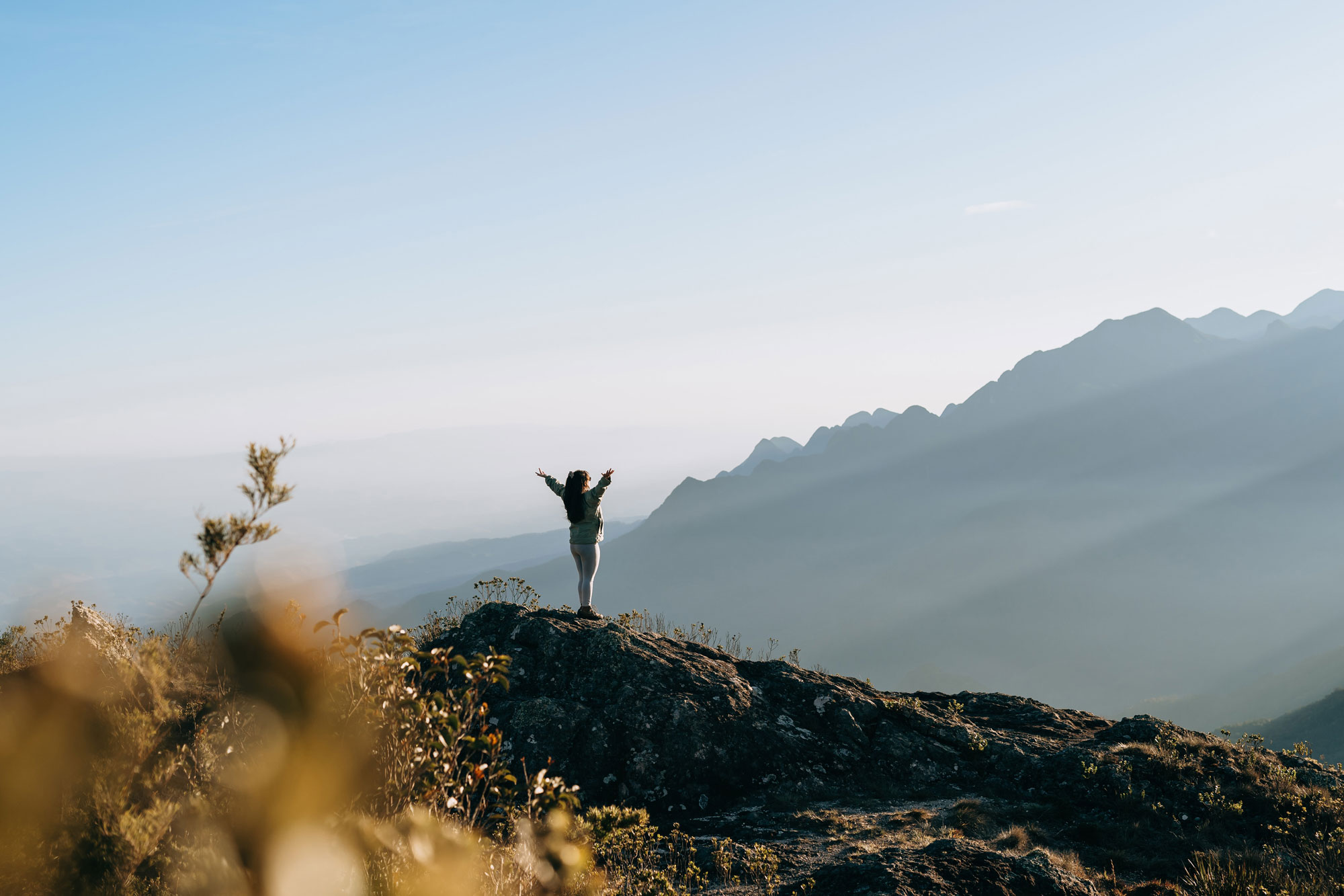 A woman holding her arms out at the top of a hill.