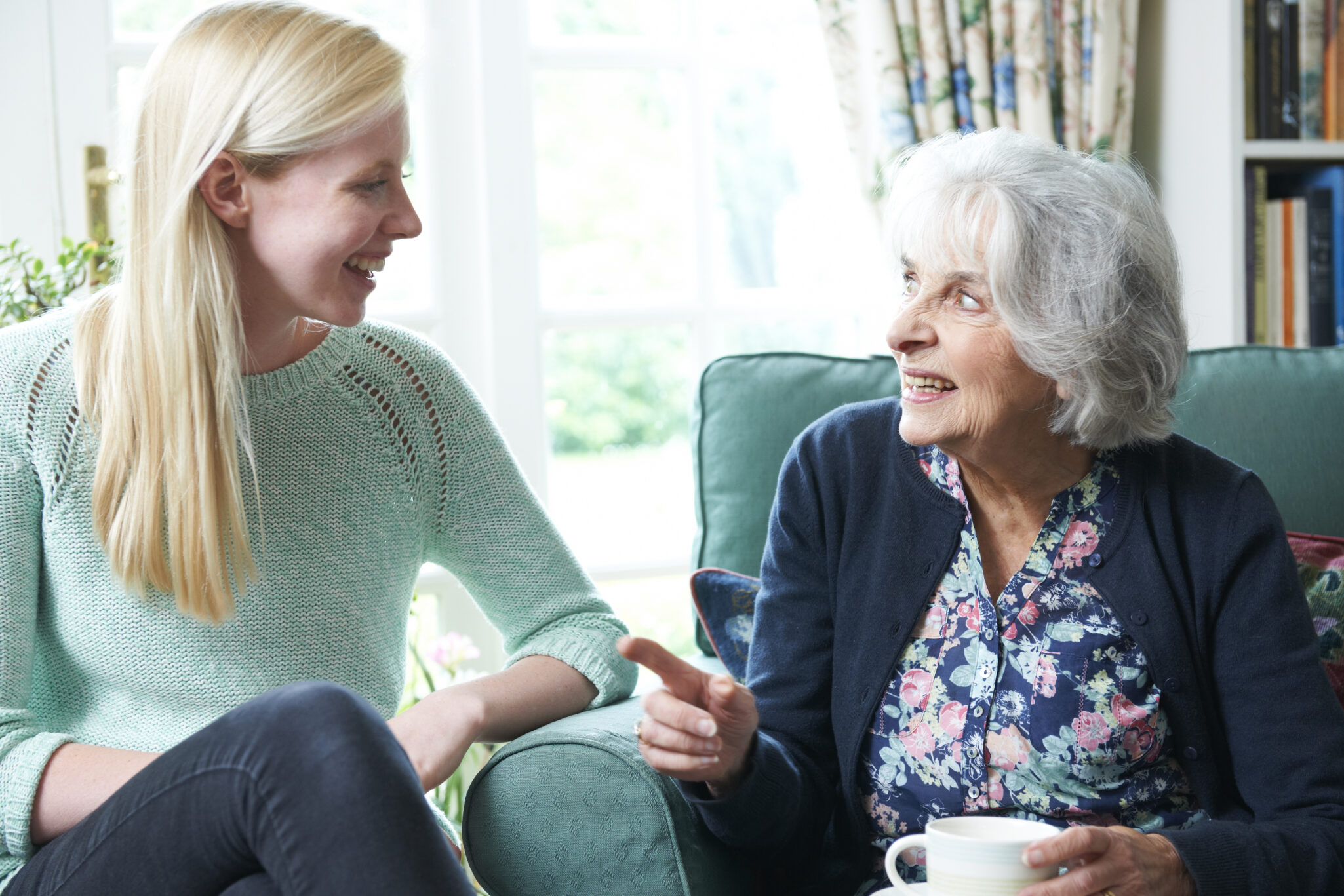 A senior woman visits with a younger blonde woman.