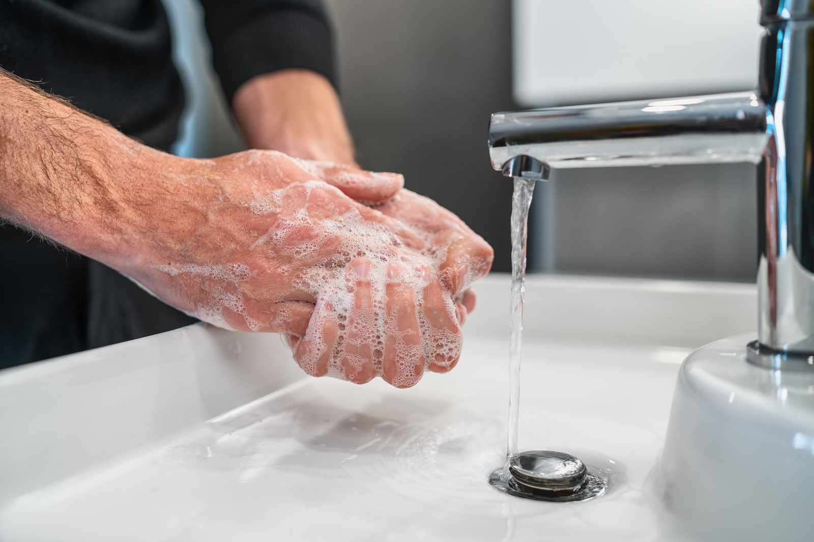 person washing their hands with soap and water in a sink