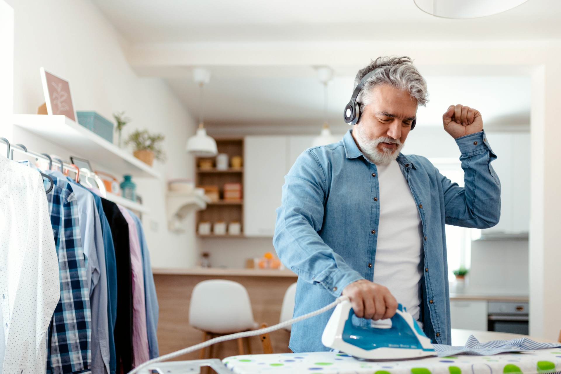 older man ironing while listening to podcast