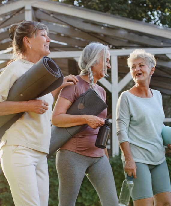 A group of senior women carrying yoga mats.