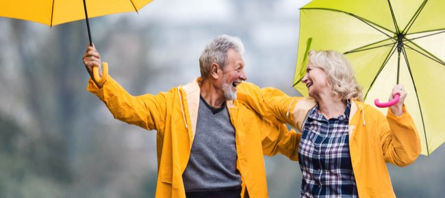 senior couple in rain jackets with umbrellas