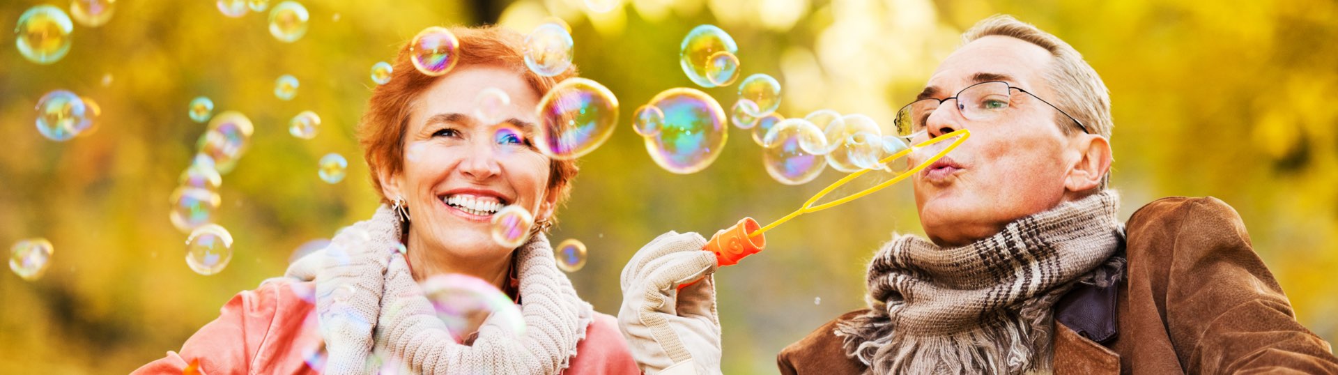 A senior couple having fun blowing bubbles outside on a fall day 