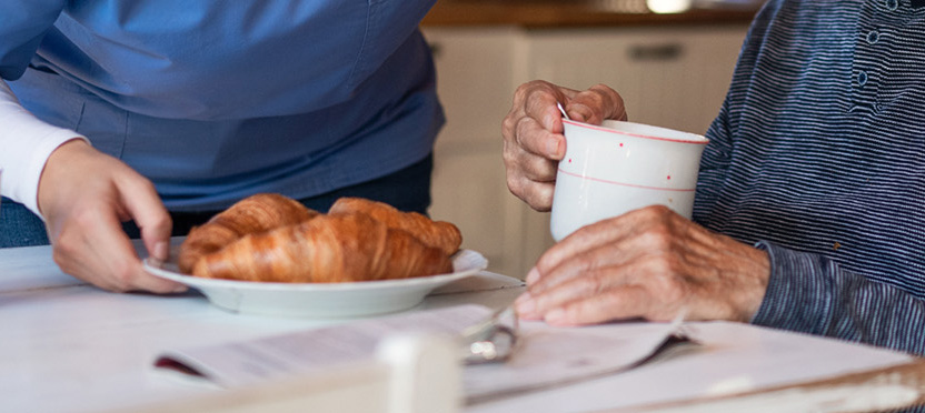 Close up of seniors enjoying croissants and coffee.