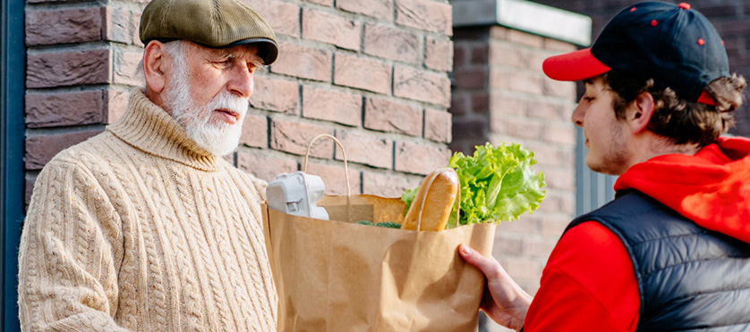 A senior man receiving a home grocery delivery.