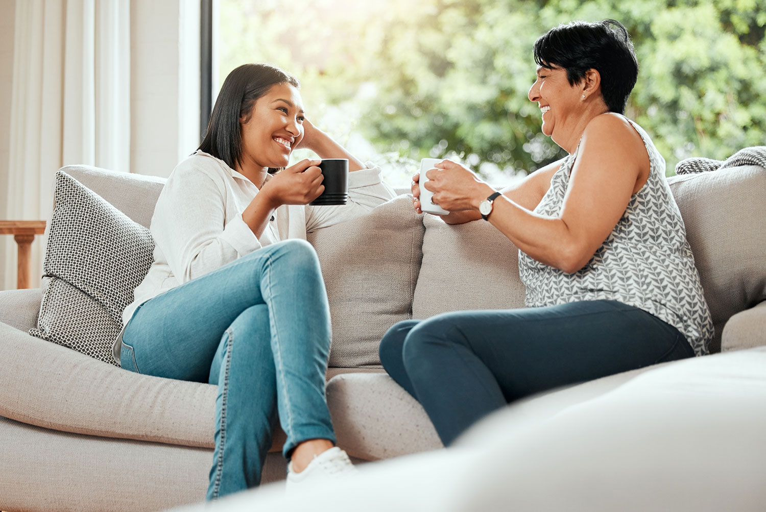mother and daughter sitting on couch drinking coffee