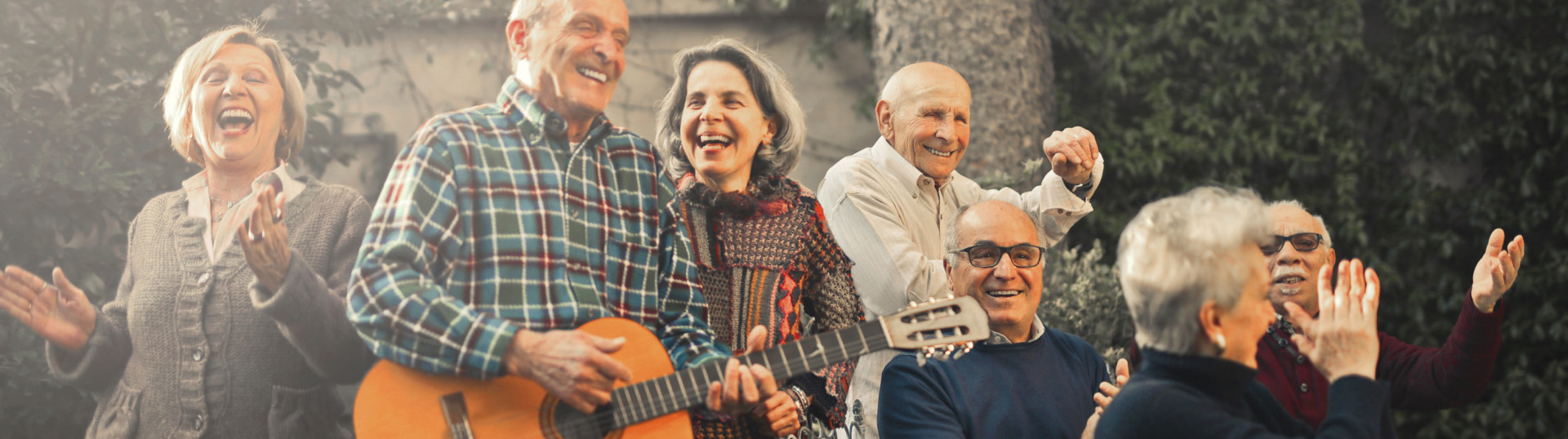 group of happy seniors listening to music and playing the guitar
