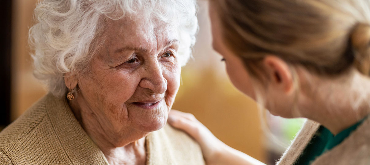 senior talking with a caregiver at a memory care facility
