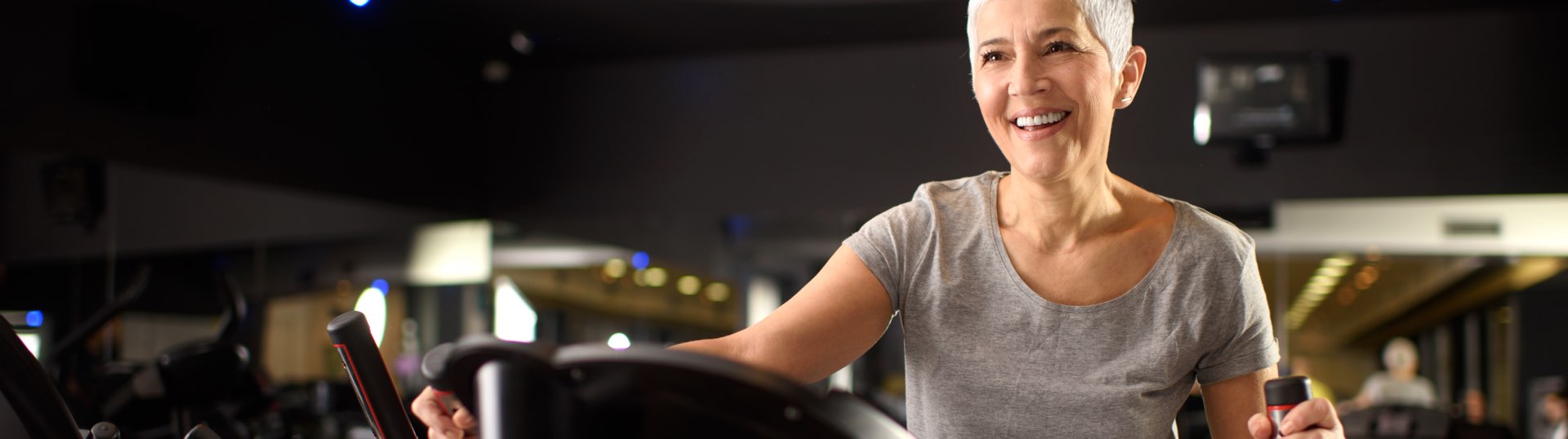 senior lady smiling as she works out on an elliptical