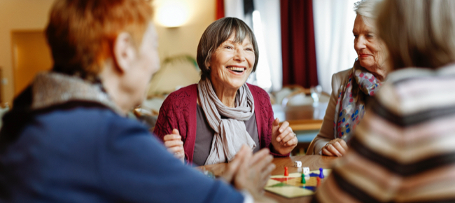 group of senior ladies smiling as they play a board game