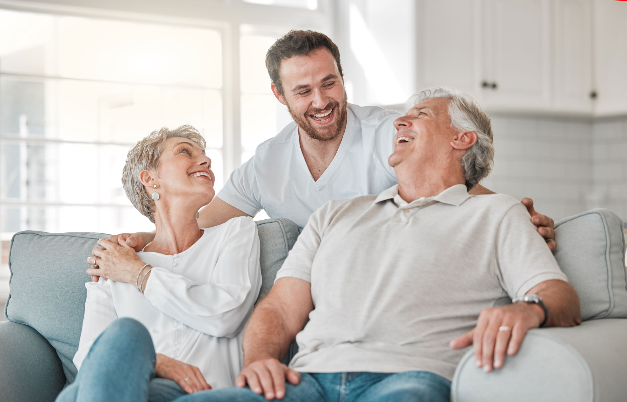 A senior couple laugh with their adult son.